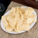 A Carlisle bone melamine oval platter with a plate of chips on a table.