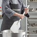 A person using an American Metalcraft stainless steel paddle to stir food in a pot.