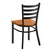 A black metal ladder back chair with a vintage wood seat.