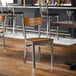 A metal chair with a clear coat finish featuring a vintage wood seat and back.