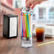 A person putting straws into a Choice plastic countertop straw dispenser on a counter.