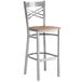 A Lancaster Table & Seating metal cross back bar stool with a wood seat.