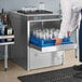 A man putting glasses in a Moyer Diebel undercounter high temperature glass washer on a bar counter.