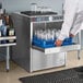 A man using a Moyer Diebel undercounter glass washer to wash glasses on a counter in a professional kitchen.