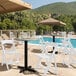 A white Lancaster Table & Seating folding chair on a patio next to a pool.