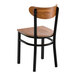 A black metal chair with a vintage wood seat and curved wood backrest.