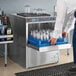 A man putting bottles in a Moyer Diebel undercounter glass washer on a counter in a professional kitchen.