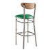 A Lancaster Table & Seating bar stool with a green vinyl seat and vintage wood back on metal legs.