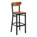 A bar stool with a black metal frame and a vintage wood seat and backrest.