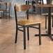 A Lancaster Table & Seating Boomerang chair with a light brown vinyl cushion and vintage wood back on a table in a restaurant.