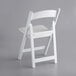 A white Lancaster Table & Seating folding chair with a white vinyl seat