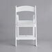 A Lancaster Table & Seating white resin folding chair with a white cushion.