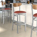 Lancaster Table & Seating Boomerang Series bar stools with burgundy seats and vintage wood backs.