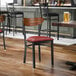 A black metal chair with a burgundy vinyl seat and a curved vintage wood backrest.