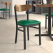 A Lancaster Table & Seating Boomerang chair with a green vinyl seat and black legs in a restaurant.