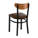 A black metal chair with a dark brown vinyl seat and a curved vintage wood backrest.