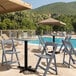 A Lancaster Table & Seating gray resin folding chair with a slatted seat next to a pool.