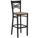 A black metal bar stool with a cross back design and a vintage wood seat.