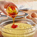 A person pouring LorAnn Oils Liquid Soy Lecithin into a bowl of dough.