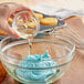 A person pouring LorAnn Preserve-It antioxidant into a bowl of blue frosting.