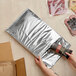 A hand opening a black Lavex insulated foam mailer.