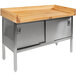 A wood top work table with a stainless steel enclosed base with sliding doors.