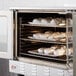 A Cooking Performance Group natural gas convection oven with trays of food inside.