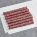 A group of thin red meat sticks on a white surface.