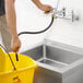 A hand holding a Regency PVC hose in a yellow bucket.