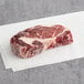 A raw Kinikin Processing ribeye steak on a white surface.