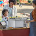 A woman and child at a food stand with a plate of fried food.