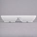 A white rectangular Carlisle double melamine ramekin on a gray surface.