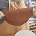 A person holding a roll of Satin Ice brown chocolate-flavored fondant.