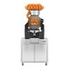 A commercial automatic feed juicer with a high-capacity orange hopper and stainless steel cabinet, designed for juicing up to 40 fruits per minute.