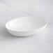 A white oval Tablecraft Sierra melamine bowl on a white surface.