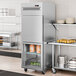 An Avantco stainless steel reach-in refrigerator with glass half doors in a large kitchen.
