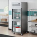 A stainless steel reach-in refrigerator with two left-hinged glass half doors and interior shelving.