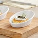 A small white Tablecraft melamine bowl with food in it.