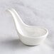 A white bowl with a long handle and a white spoon on top.