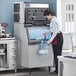 A woman pouring ice from an Avantco Ice storage bin into a plastic container.