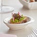 A Tablecraft white mini melamine bowl with food on it.