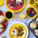 A table in a breakfast diner set with Fiesta Sunflower China Bouillon bowls filled with blueberries and strawberries.