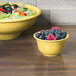 A Fiesta china bowl filled with salad and fruit including blueberries and raspberries.