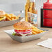 A Tablecraft stainless steel rectangular serving basket with a burger and fries.