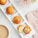A plate with three Rich's Ready-to-Finish Jumbo Birthday Cake Filled Donut Bites with red sprinkles on them next to a cup of coffee.
