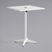 A white table with a metal base and umbrella hole.
