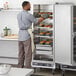 A man in an apron putting food in a ServIt holding cabinet.