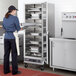 A woman in a white coat using a ServIt holding and proofing cabinet with a clear door.