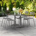 A Lancaster Table & Seating matte gray aluminum dining height table with chairs on an outdoor patio.