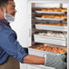 A man opening clear dutch doors on a ServIt holding cabinet on a counter.